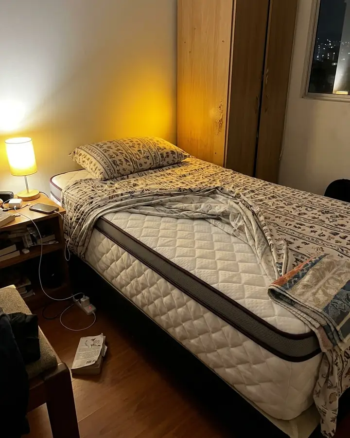 Pillow en una cama sencilla de un apartamento, con la sábana a medio poner